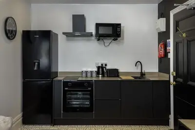 a kitchen with black appliances and a black refrigerator at St Chads Suites by Central Beach Leisure in Blackpool
