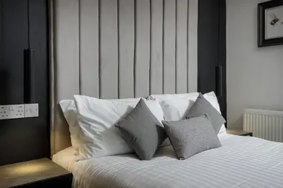 a bedroom with a bed with white pillows at St Chads Suites by Central Beach Leisure in Blackpool