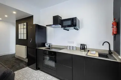 a kitchen with black cabinets and a sink and a microwave at St Chads Suites by Central Beach Leisure in Blackpool