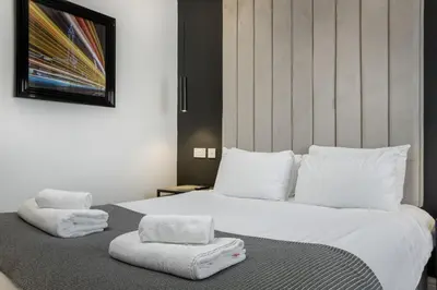 a bedroom with a large white bed with towels on it at St Chads Suites by Central Beach Leisure in Blackpool
