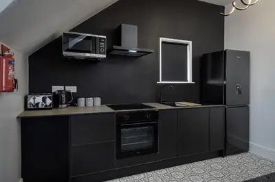 a black kitchen with a stove and a microwave at St Chads Suites by Central Beach Leisure in Blackpool