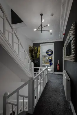 a hallway with a white staircase with a chandelier at St Chads Suites by Central Beach Leisure in Blackpool