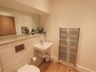 a bathroom with a sink and a toilet and a mirror at The Mabel Suite Stone Cross Mansion in Ulverston