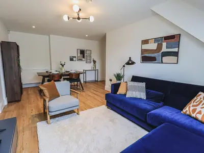 a living room with a blue couch and a dining room at The Mabel Suite Stone Cross Mansion in Ulverston