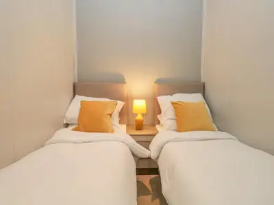 two beds in a room with a lamp on a table at Yealand 36 in Carnforth