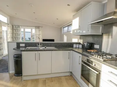a kitchen with white cabinets and a stove top oven at Yealand 36 in Carnforth