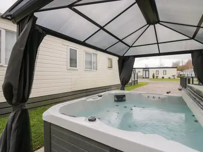 a hot tub with an umbrella in a backyard at Yealand 36 in Carnforth