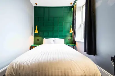 a bedroom with a bed with a green wall at The Luxury Penthouse by Sasco Apartments in Blackpool