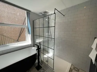 a bathroom with a shower with a tub and a window at The Luxury Penthouse by Sasco Apartments in Blackpool