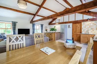 a dining room and living room with a wooden table at Ingleborough View in Carnforth