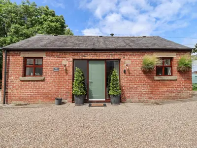 a red brick house with potted plants in front of it at The Stables in Preston