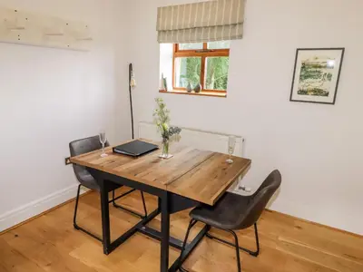 a dining room table with chairs and a laptop on it at The Stables in Preston