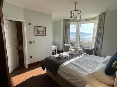 a bedroom with a bed and a large window at Victoria Mount in Grange Over Sands