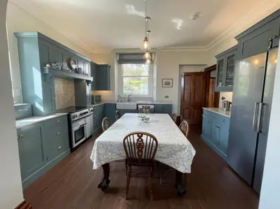 a kitchen with blue cabinets and a table with chairs at Victoria Mount in Grange Over Sands