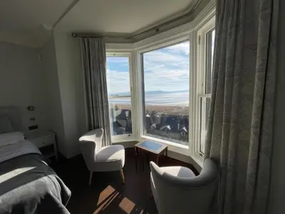 a bedroom with a large window with two chairs and a bed at Victoria Mount in Grange Over Sands