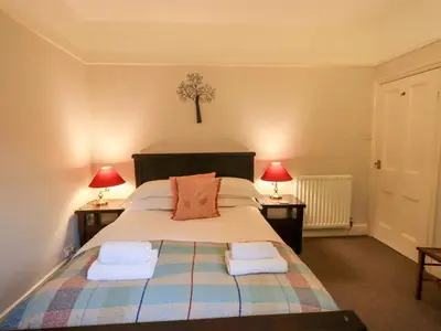 a bedroom with a large bed with two lamps at Yewbarrow Cottage in Grange Over Sands
