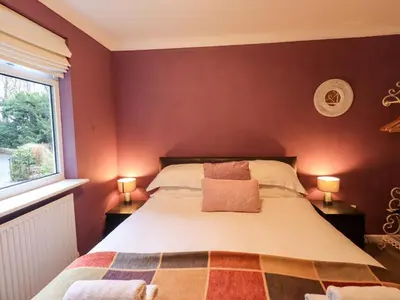 a bedroom with a large bed with two lamps at Yewbarrow Cottage in Grange Over Sands