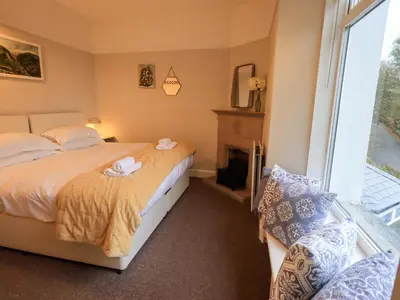 a bedroom with a bed and a fireplace and a window at Yewbarrow Cottage in Grange Over Sands