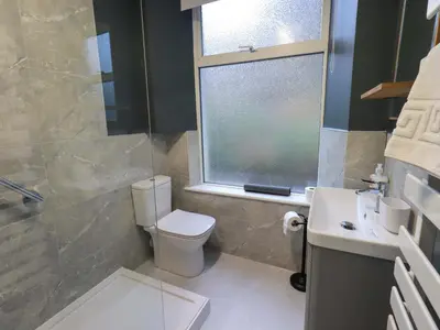 a bathroom with a toilet and a sink and a window at Yewbarrow Cottage in Grange Over Sands