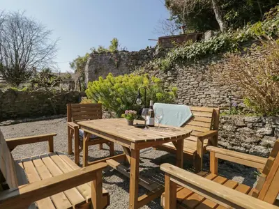 a wooden table and chairs in a garden at Yewbarrow Cottage in Grange Over Sands