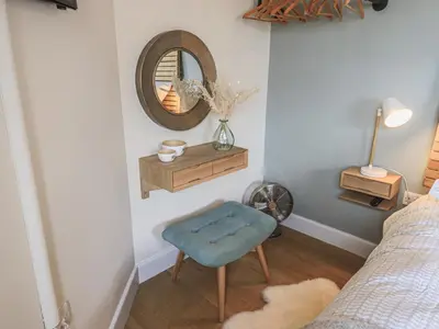 a bedroom with a blue stool and a mirror at Oversands Cottage in Grange Over Sands