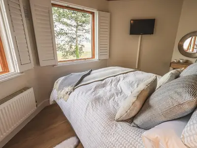 a bedroom with a bed and a window at Oversands Cottage in Grange Over Sands