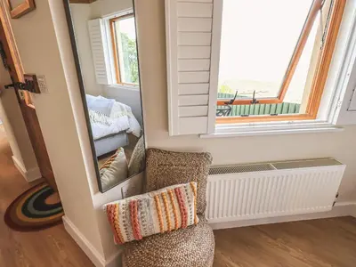 a room with a chair and a window at Oversands Cottage in Grange Over Sands