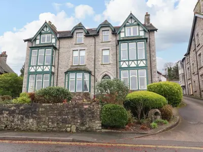 an old stone house with green and white windows at Inglewood Court in Carnforth