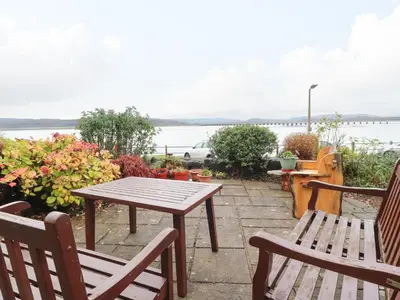 a picnic table and chairs on a patio overlooking the water at Inglewood Court in Carnforth