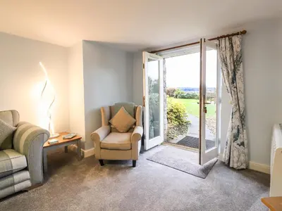 a living room with a chair and a sliding glass door at Inglewood Court in Carnforth
