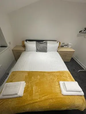 a bedroom with a large bed with a yellow blanket at PCK THAS HOTEL in Blackpool