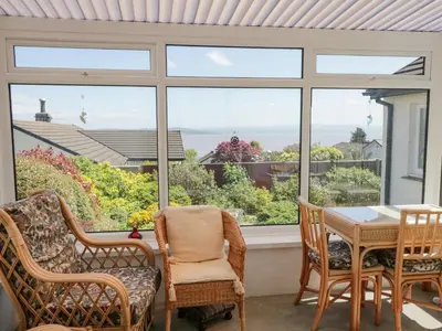 a dining room with a table and chairs and a large window at Westwinds in Grange Over Sands