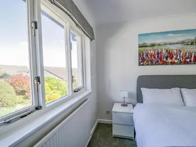 a bedroom with a bed and two windows at Westwinds in Grange Over Sands