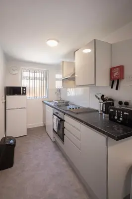 a kitchen with white cabinets and a black counter top at Jellyfish Apartments in Blackpool