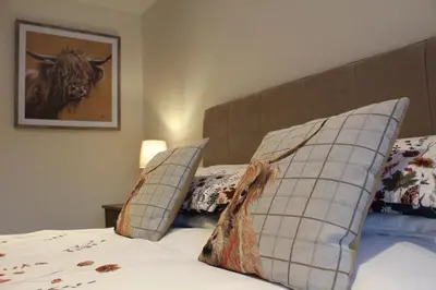 a bedroom with a bed with pillows and a cow picture at Whitebrook Cottage in Mellor