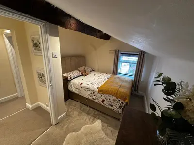 a small bedroom with a bed and a window at Whitebrook Cottage in Mellor