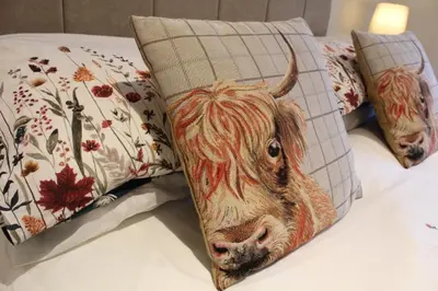 a pillow with a picture of a cow on a bed at Whitebrook Cottage in Mellor