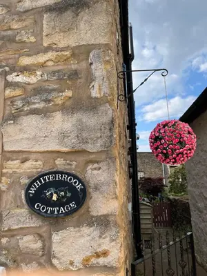 a sign on the side of a stone wall at Whitebrook Cottage in Mellor
