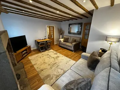 a living room with a couch and a tv at Whitebrook Cottage in Mellor