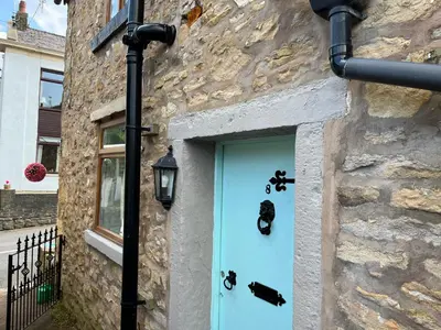 a blue door on a stone building with a street light at Whitebrook Cottage in Mellor