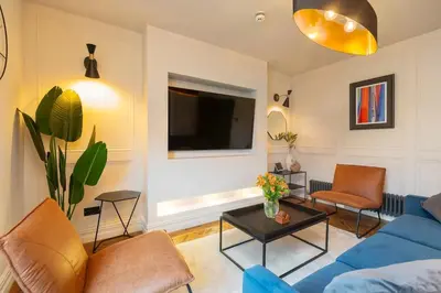 a living room with a blue couch and a tv at Capri Stays - Apartment Two - Two Bed Apartment in Blackpool