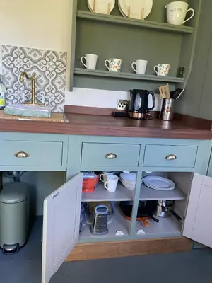 a kitchen with a blue cabinet with cups and dishes at Heywood Glamping in Ormskirk
