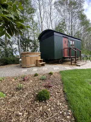 a green and black tiny house with a wooden tub at Heywood Glamping in Ormskirk