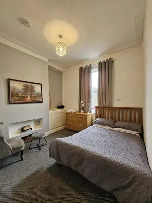 a bedroom with a bed and a chair and a window at Cheerful 4 bedroom close to Uclan, Preston City Center in Preston