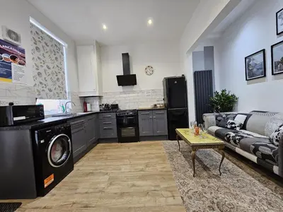 a living room with a couch and a kitchen at Cheerful 4 bedroom close to Uclan, Preston City Center in Preston