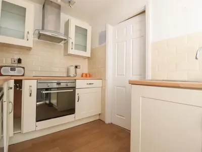 a kitchen with white cabinets and a stove top oven at The Mews Cottage in Lytham St Annes