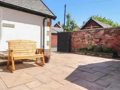a wooden bench sitting outside of a house at The Mews Cottage in Lytham St Annes