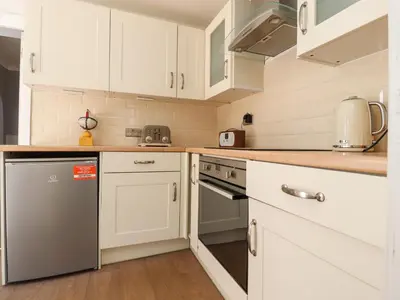 a kitchen with white cabinets and a dishwasher at The Mews Cottage in Lytham St Annes