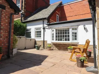 a patio with a wooden bench in front of a house at The Mews Cottage in Lytham St Annes