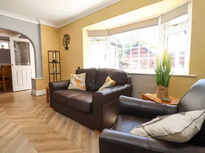 a living room with a leather couch and a table at The Mews Cottage in Lytham St Annes